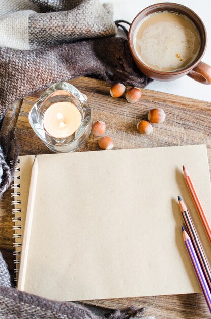 Cuaderno vintage con lápices, vela y café.