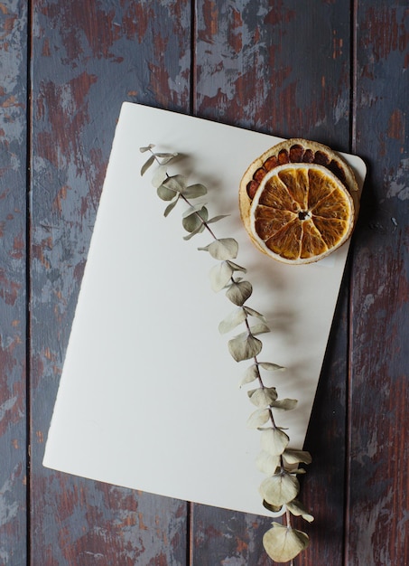 Cuaderno vintage y rodajas de naranja secas en una mesa de madera rústica