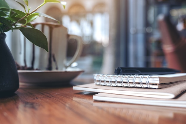 Cuadernos, bolígrafo y taza de café en la mesa de madera