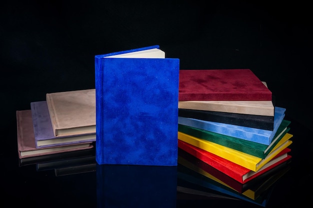 Foto cuadernos de diferentes colores sobre un fondo negro