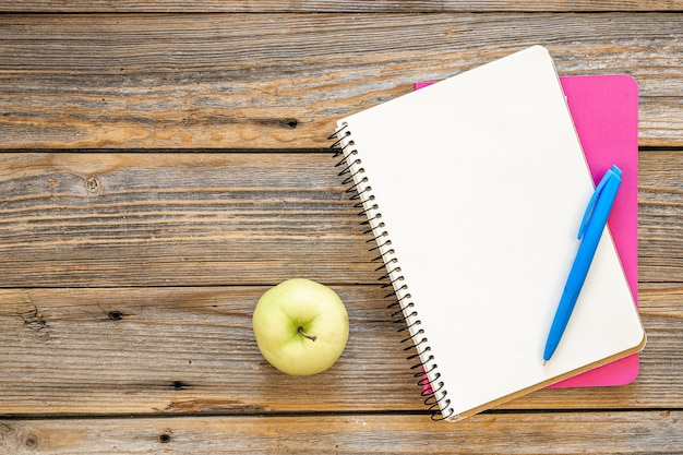 Cuadernos y una manzana en un fondo de madera vista superior