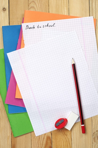 Cuadernos multicolores lápiz y sábana en blanco sobre la mesa