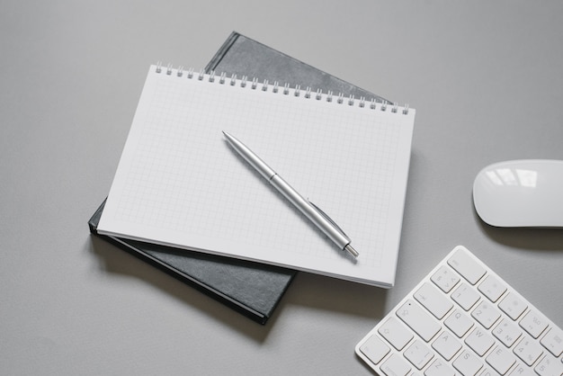 Cuadernos con una página en blanco y un bolígrafo encima cerca del hardware