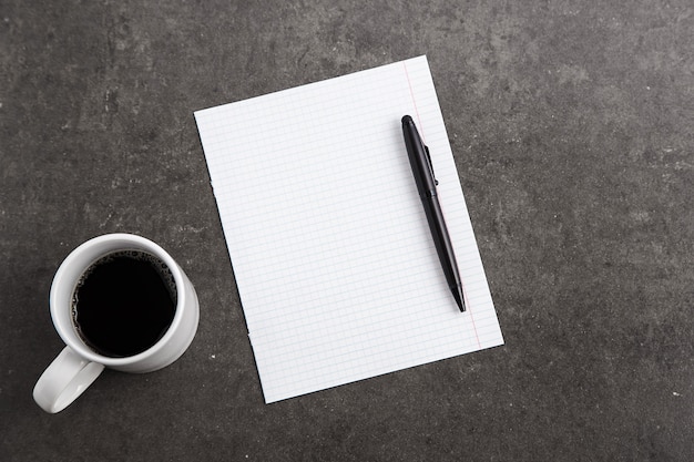 Cuadernos, taza de café y vasos de mármol gris.