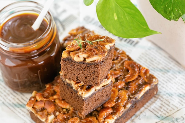 Foto cuadrado marrón dorado de rebanada de pastel de toffee con nuez de cajú y salsa de caramelo