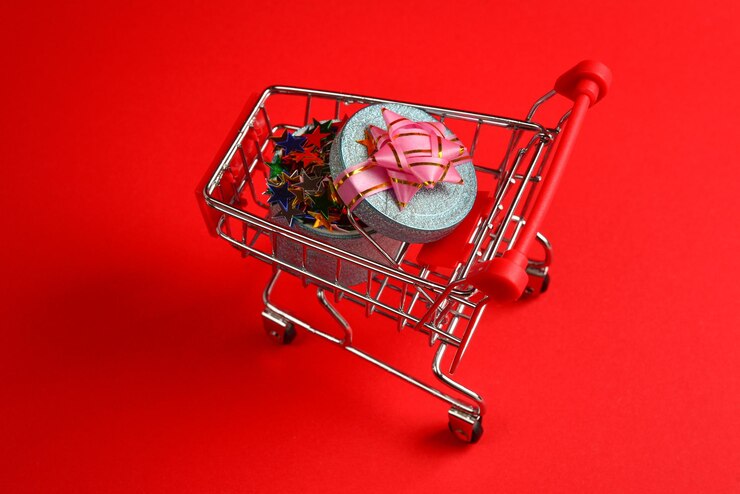 Foto cuadro actual azul con lazo rosa en un carrito de compras sobre un fondo rojo.