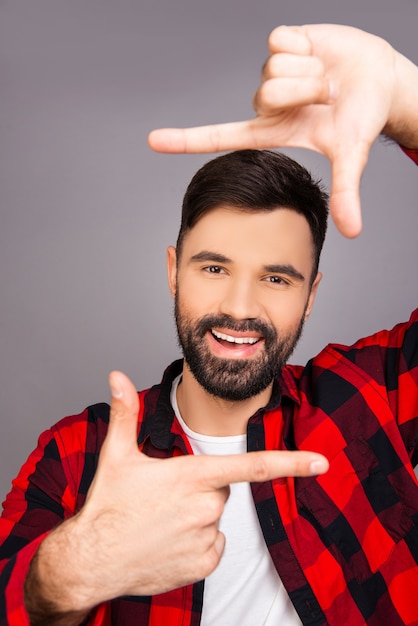 Cuadro. Hombre joven feliz haciendo marco con los dedos