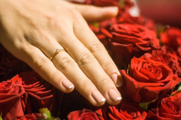 Cuadro de la mano de la mujer con el anillo de bodas en rosas