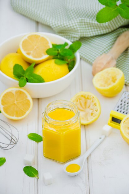 Cuajada de limón casera en frasco de vidrio con limones frescos sobre una mesa blanca