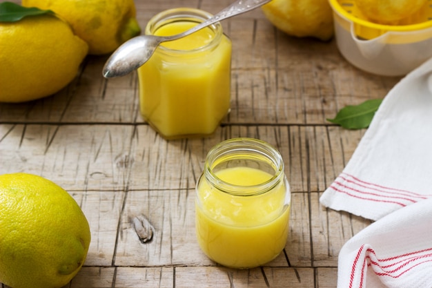 Cuajada de limón casera con tarros y limones sobre fondo de madera