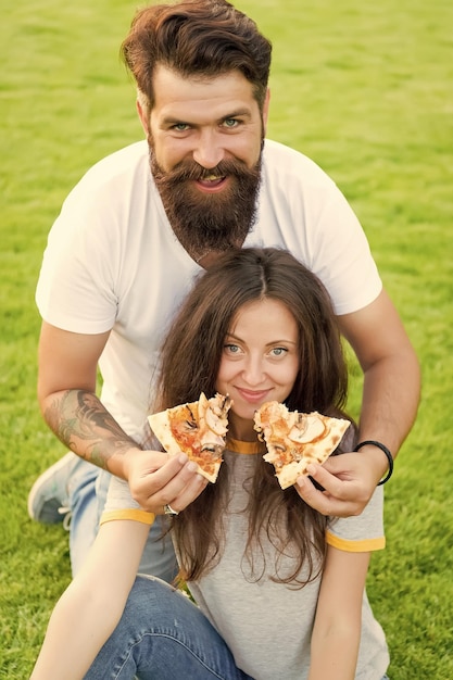 ¿Cuál es tu comida rápida favorita? Hombre barbudo alimentando a una mujer con pizza cursi Pareja enamorada saliendo al aire libre come pizza Estudiantes hambrientos compartiendo comida Pareja comiendo pizza relajándose en el césped Fin de semana familiar