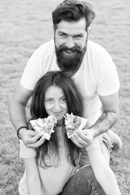 ¿Cuál es tu comida rápida favorita? Hombre barbudo alimentando a una mujer con pizza cursi Pareja enamorada saliendo al aire libre come pizza Estudiantes hambrientos compartiendo comida Pareja comiendo pizza relajándose en el césped Fin de semana familiar