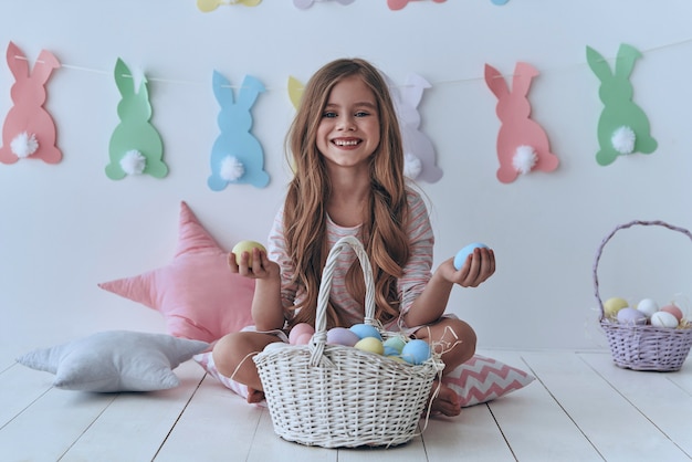 ¿Cuál quieres? Niña linda con huevos de Pascua y sonriendo