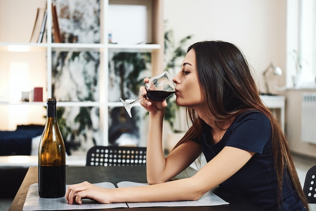 Foto cuando entra el vino salen cosas raras jovencita bebiendo vino tinto sola