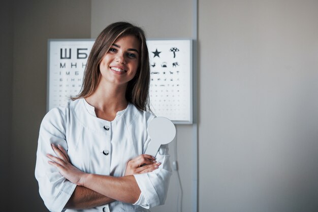 Cuando estás enamorado de tu trabajo. Hermosa doctora de pie en la oficina con las manos cruzadas