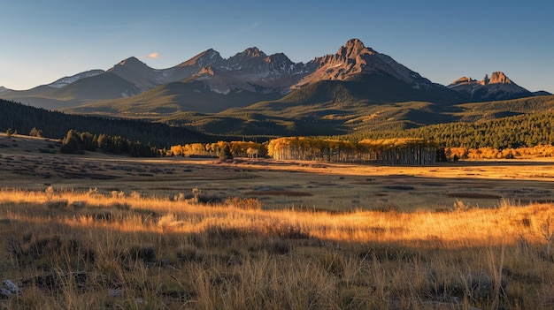 Cuando el sol se pone detrás de los escarpados picos, el pasto de montaña de otoño se baña en un resplandor dorado, proyectando largas sombras que bailan sobre el paisaje ondulado.