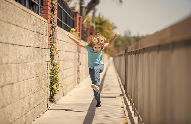 Cuando viva una vida activa, sea feliz y enérgico Niño enérgico corra en el paseo marítimo Infancia divertida