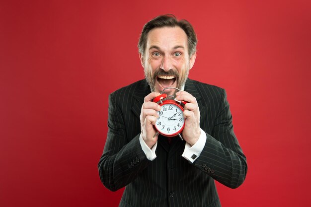 Foto cuánto tiempo queda hasta la fecha límite. gerente con despertador. hombre de negocios barbudo mantenga el reloj. barba de hombre maduro lista para empezar a trabajar. tiempo de trabajar. el hombre de negocios se preocupa por el tiempo. habilidades de manejo del tiempo.