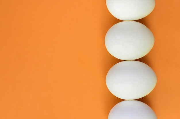 Unos cuantos huevos de pascua blancos en una naranja brillante