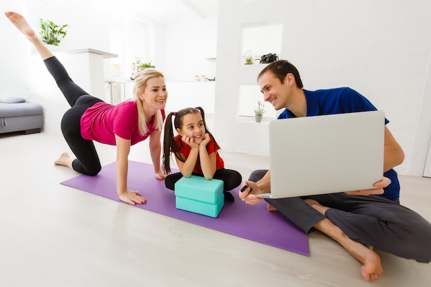 Cuarentena en casa. Niña haciendo yoga olnline en un portátil durante la cuarentena de autoaislamiento