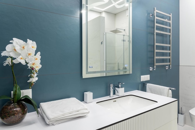 Cuarto de baño azul y blanco con iluminación de toallas de espejo grande y lavabo de encimera