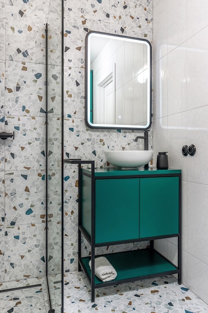 Cuarto de baño con muebles turquesa, grifos negros y ducha.