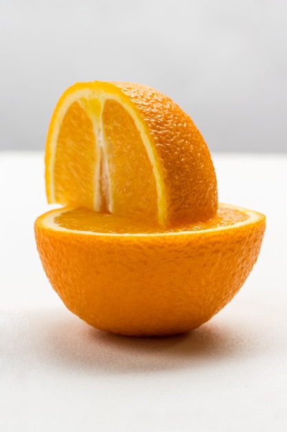 Un cuarto de naranja sobre la mitad de una naranja. De cerca
