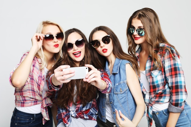 Cuatro adolescentes felices con smartphone tomando selfie