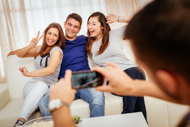 Cuatro alegres mejores amigos pasando un buen rato en un apartamento y tomándose una foto.