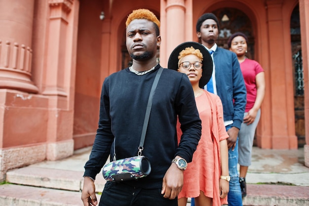 Cuatro amigos africanos posaron al aire libre contra la arquitectura antigua. Dos chicas negras con chicos.