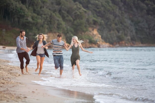 Cuatro amigos felices corriendo en la playa