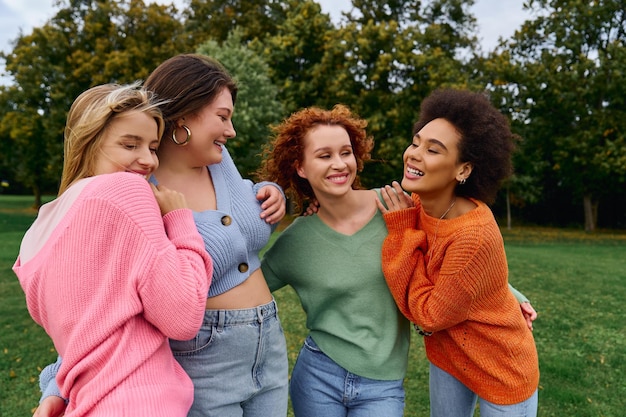 Cuatro amigos de moda disfrutando de una alegre tarde de primavera en un vibrante parque verde
