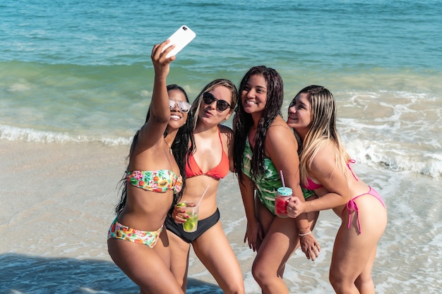 Cuatro amigos usando el móvil en la playa.