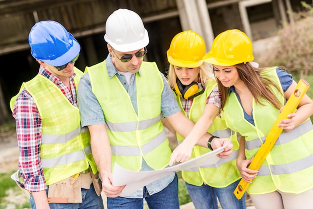 Foto cuatro arquitectos de la construcción revisan el plan en un sitio de construcción.