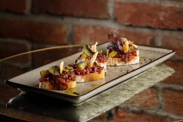 Cuatro bruschettas con tartar de ternera en un plato Crostini con tartar de ternera Sándwich de bruschetta de ternera con ternera gourmet cruda