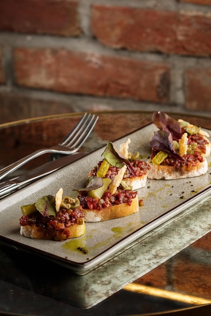 Foto cuatro bruschettas con tartar de ternera en un plato crostini con tartar de ternera sándwich de bruschetta de ternera con ternera gourmet cruda