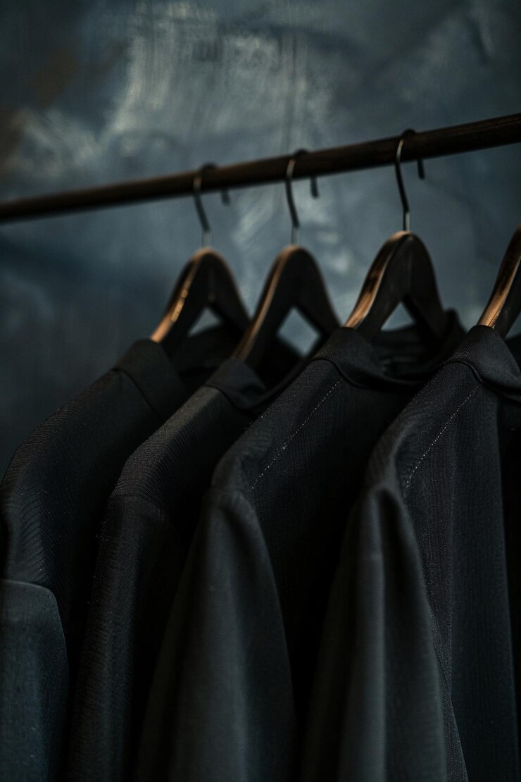 Cuatro camisas negras colgando de una barandilla de ropa exudan un aire de uniformidad pulida