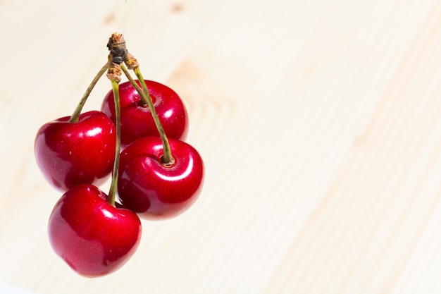 Cuatro cerezas dulces orgánicas aisladas en un fondo de madera