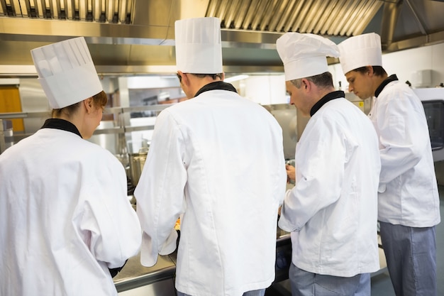 Foto cuatro cocineros trabajando en cocina industrial