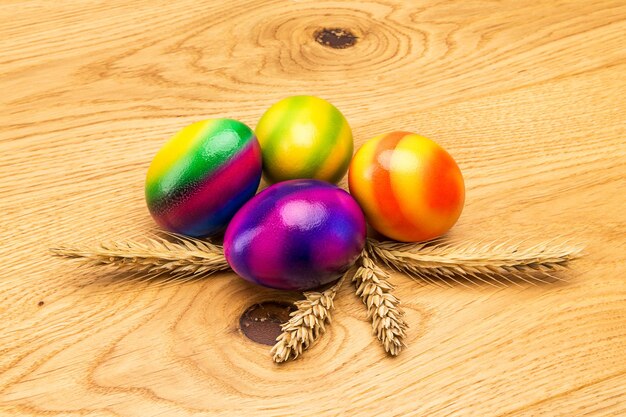 Cuatro coloridos huevos de pascua en diferentes colores con cereales sobre fondo de madera. Tomada en estudio con una 5D mark III.