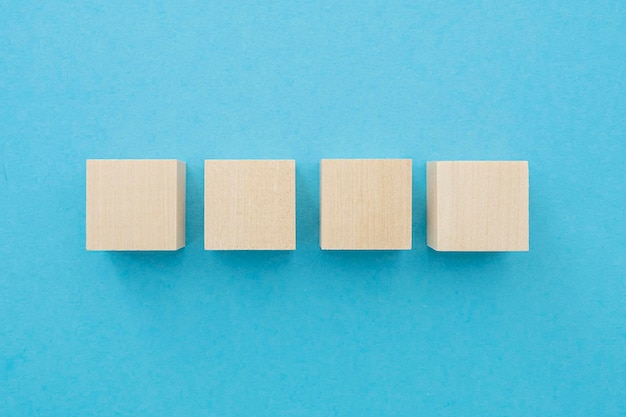 Cuatro cubos de madera de forma cuadrada con superficie en blanco sobre fondo azul para ideas de concepto de negocio