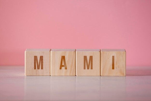Cuatro cubos de madera con la palabra escrita quotmamiquot sobre fondo rosa