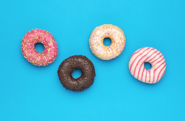 Cuatro donuts glaseados multicolores sobre un fondo azul El concepto mínimo de horneado popular