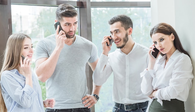 Cuatro empleados jóvenes Dos empleados hombres y dos mujeres se comunican en una conversación informal