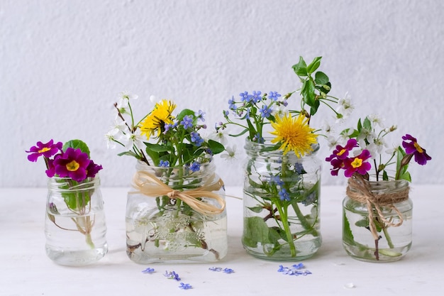 Cuatro frascos de vidrio de flores con uno que dice 'primavera'