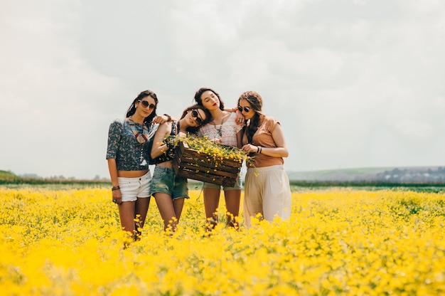 Cuatro hermosa chica hippie en un campo de flores amarillas.
