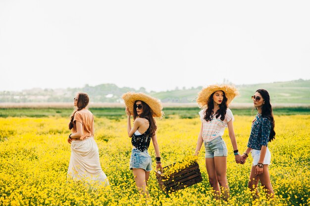 Cuatro hermosa chica hippie en un campo de flores amarillas.