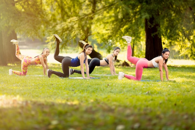 Cuatro hermosas amigas haciendo ejercicio en el parque. Mirando a la cámara.