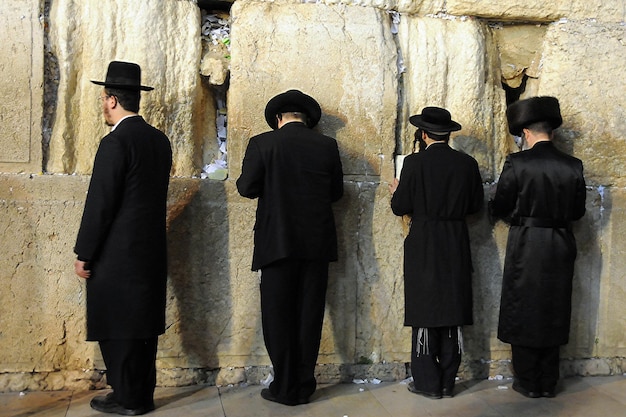 Foto cuatro hombres orando en el muro occidental de jerusalén