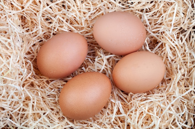 Cuatro huevos marrones en una cama de paja